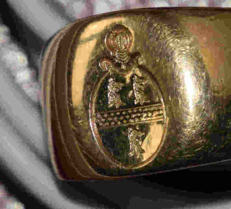 d'azur à la fasce d'or accompagnée de trois têtes de coq du même